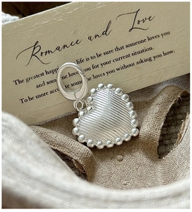 Detail of S925 sterling silver heart pendant with striped texture and beaded border