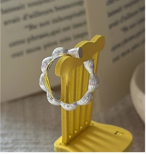 Detailed view of S925 sterling silver wavy open ring on a miniature yellow chair
