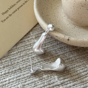 Minimalist S925 sterling silver matte teardrop earrings on beige woven fabric texture