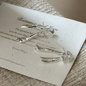 Elegant S925 sterling silver bow earrings on white card with knit fabric background