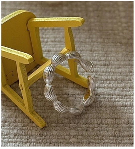Macro shot of S925 sterling silver croissant ring with textured ridges on a yellow prop