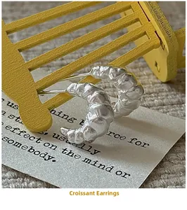 Detail of S925 sterling silver croissant earrings with matte finish and pleated texture