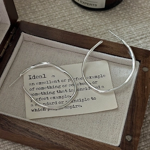 Minimalist S925 sterling silver wavy hoop earrings on a vintage wooden jewelry box