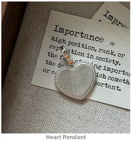Gros plan du pendentif coeur en argent avec texture brossée et bord perlé sur carte rétro