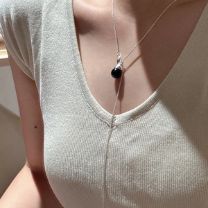 Minimalist S925 sterling silver necklace with black sphere pendant on beige sweater