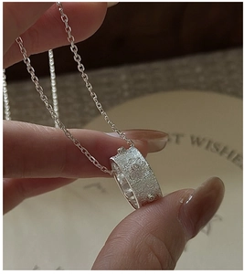 Macro d'un collier en argent S925 avec relief floral vintage et texture martelée