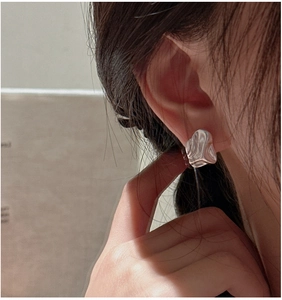 Close-up of S925 sterling silver earring featuring irregular liquid ripple texture on ear
