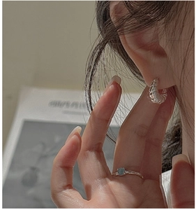 Detailed view of silver croissant hoop earring with twisted texture and blue gemstone ring