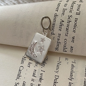 S925 sterling silver rectangular crescent moon and star pendant on a vintage book page