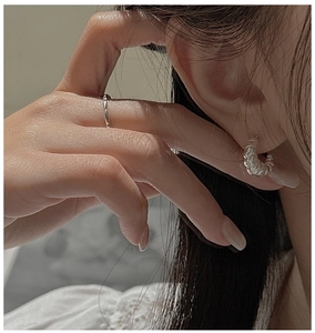 Close-up of S925 sterling silver croissant hoop earring and twisted rope ring texture