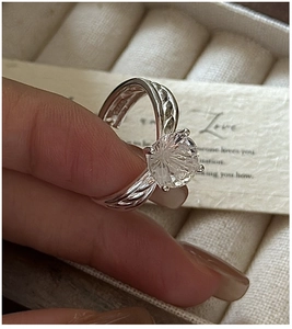 Close-up of a S925 silver ring with white crystal in six-prong setting on a hand
