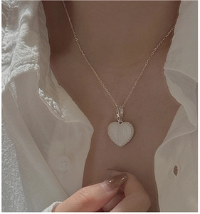 Détail d'un pendentif cœur en argent sterling S925 avec une finition blanche texturée