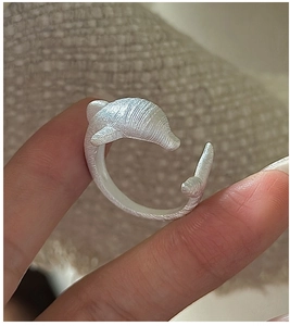 Macro shot of silver dolphin ring with brushed texture and adjustable open band detail