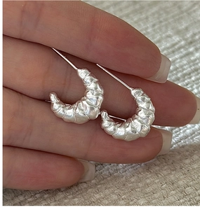 Macro detail of S925 sterling silver croissant earrings with hammered texture finish