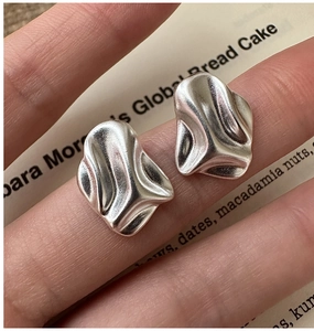 Close-up of S925 sterling silver earrings with textured irregular geometric surface
