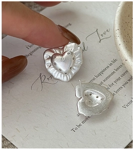 Detail of S925 silver heart stud earrings with wrinkled texture and pavé white zircon