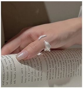 Detailed view of dolphin ring on thumb featuring frosted silver finish and open band design