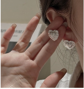 Macro detail of silver heart stud earrings with vintage wrinkled texture and wavy edges