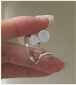 Macro detail of S925 sterling silver ring featuring brushed metal disks and wavy band