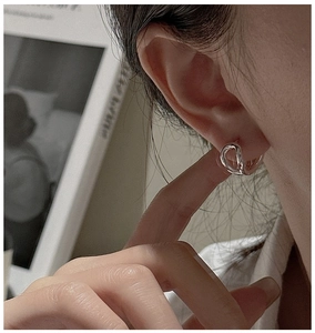 Macro view of S925 sterling silver curved hoop earrings with minimalist knotted design