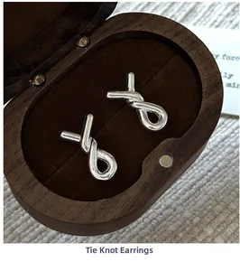Macro shot of silver knot earrings placed on a brown velvet wooden jewelry box