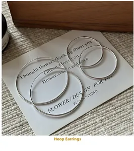 Macro detail of S925 sterling silver hoop earrings in two sizes on minimalist background