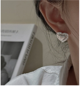 Close-up of S925 sterling silver heart earrings with vintage wrinkled texture on ear