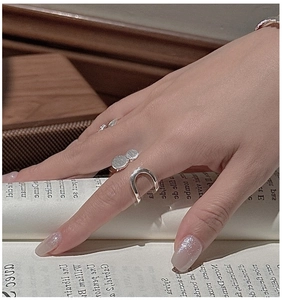 Detail of S925 sterling silver layered rings worn by a model over an open vintage book