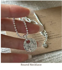 Macro detail of S925 sterling silver hammered disc pendant and beaded chain necklace