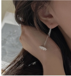Detail of silver long-drop floral earrings worn to show the elegant artistic design