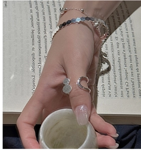 Detail of layered S925 sterling silver rings and faceted bracelet on a female hand