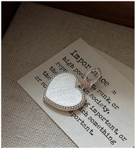 Détail d'un pendentif cœur en argent S925 avec texture brossée et bord perlé