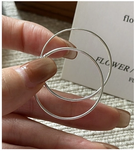 Macro view of polished S925 sterling silver hoop earrings held by hand for detail