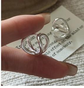 Macro shot of minimalist S925 sterling silver hoop earrings with woven multi-loop design