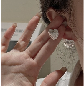 Close-up of S925 sterling silver heart earrings with vintage wrinkled texture on model