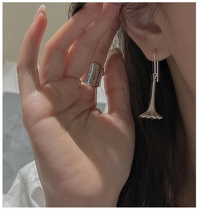 Detail of silver drop earrings and wide ring set worn by model in a soft lighting