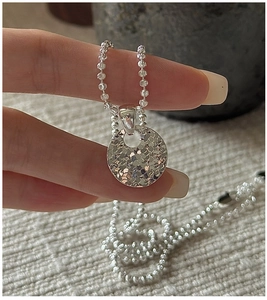 Detail of 925 sterling silver ball chain necklace featuring a hammered circular pendant