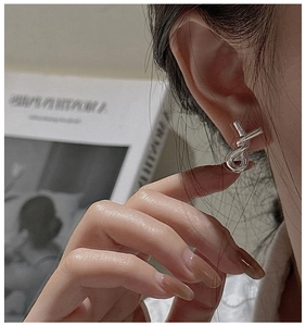 Detailed close-up of a twisted silver knot earring worn on the ear for a trendy minimalist look