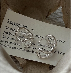 Close-up of twisted silver hoop earrings on vintage paper background with artistic vibe