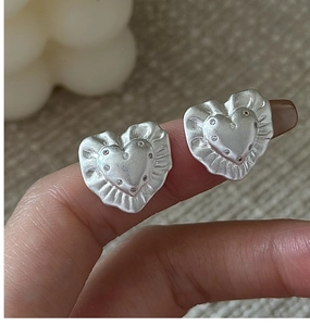 Close-up of S925 sterling silver heart studs with textured edges and tiny zircons