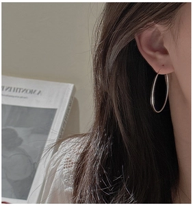 Close-up of model wearing large S925 sterling silver hoop earrings in a minimalist style