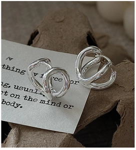 Macro shot of polished S925 sterling silver multi-layered curved earrings on paper card