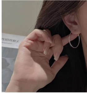 Close-up of minimalist S925 sterling silver hoop earring on model with high gloss finish