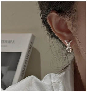 Detail of S925 sterling silver knot earrings worn on ear in a vintage aesthetic setting