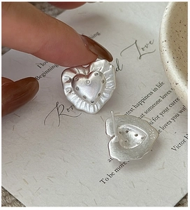Macro detail of S925 sterling silver heart earrings with brushed texture and S925 hallmark