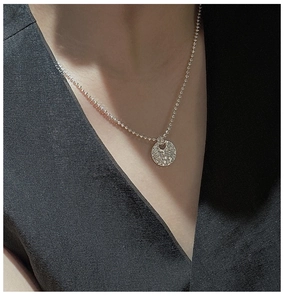 Macro shot of a 925 sterling silver hammered disc pendant necklace on a model