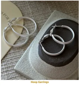 Detailed view of matte S925 silver hoop earrings set on elegant ceramic display