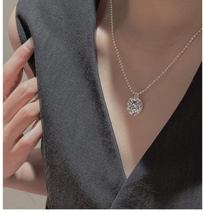 Macro detail of 925 sterling silver round pendant with irregular embossed texture on bead chain