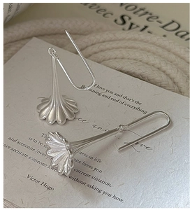Detail of matte silver flower earrings with long French hooks on artistic paper card