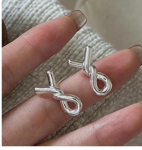 Close-up of S925 sterling silver twist knot earrings with a polished finish held by hand